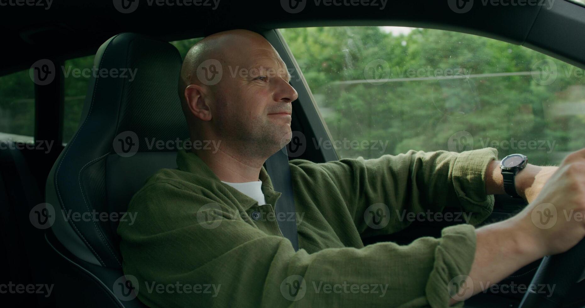 A man smiles and dances while driving a car. View from the car interior. Summer day photo
