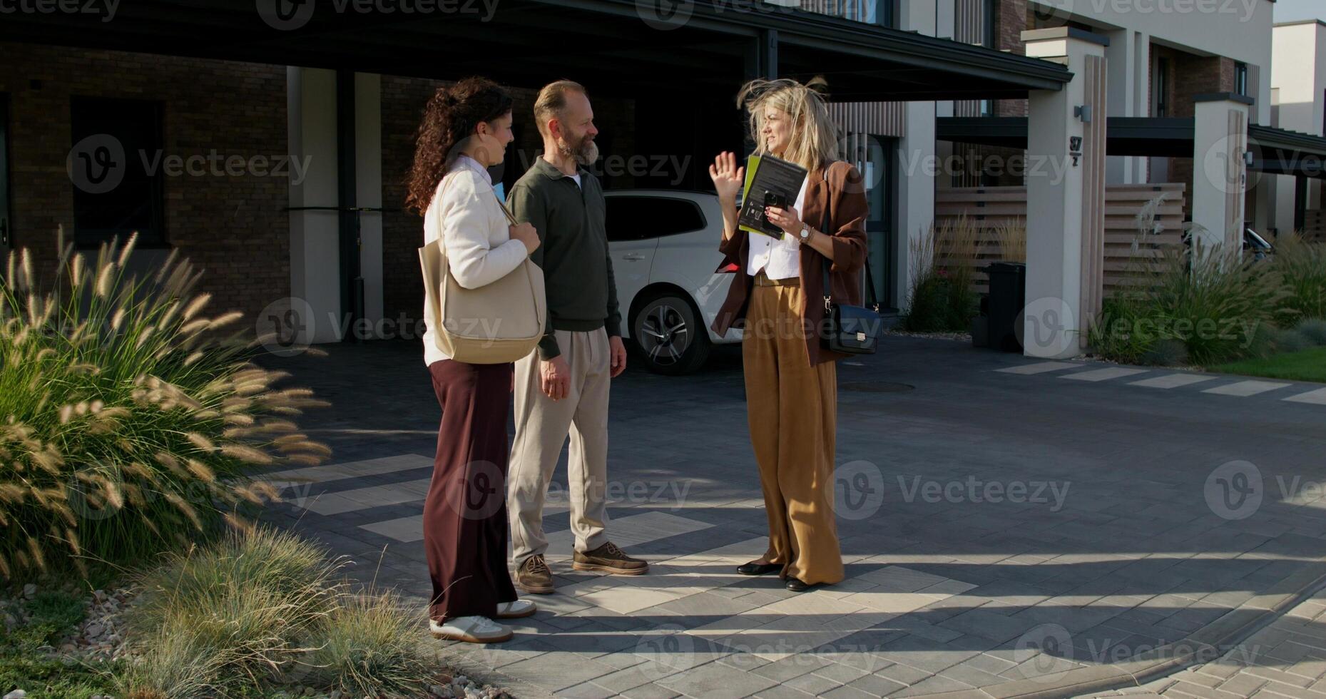 The realtor shows the booklet to customers standing near the townhouse for sale photo