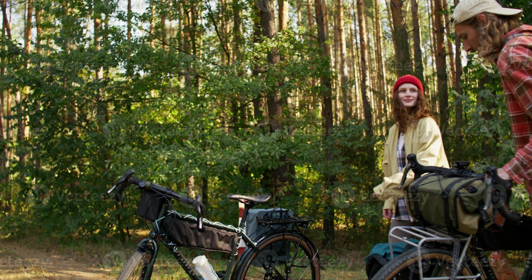 A man and a woman get on their bicycles and start riding through the forest on a sunny day photo