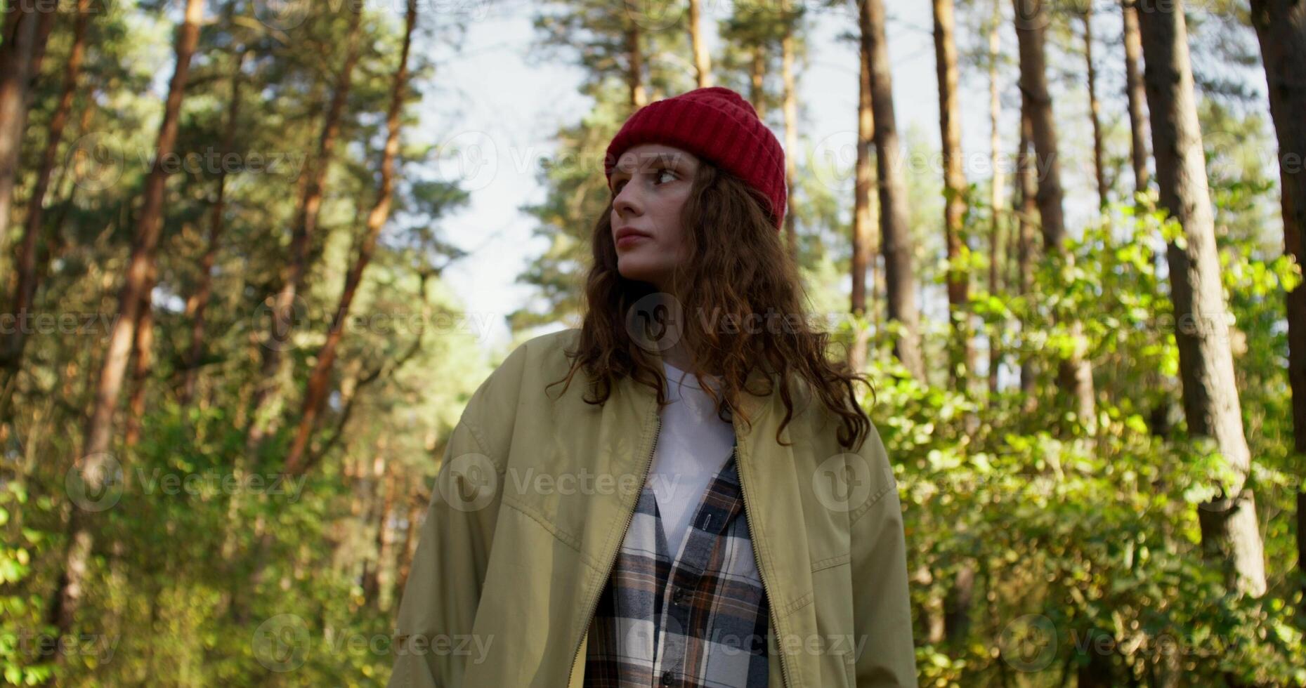 A young woman walks slowly through the forest, she looks around with a calm look. Sunlight photo