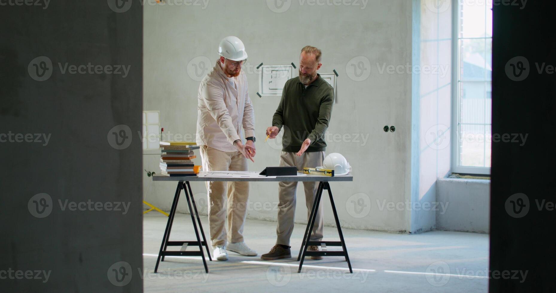 The foreman and the customer are discussing the house project. They use a tablet photo