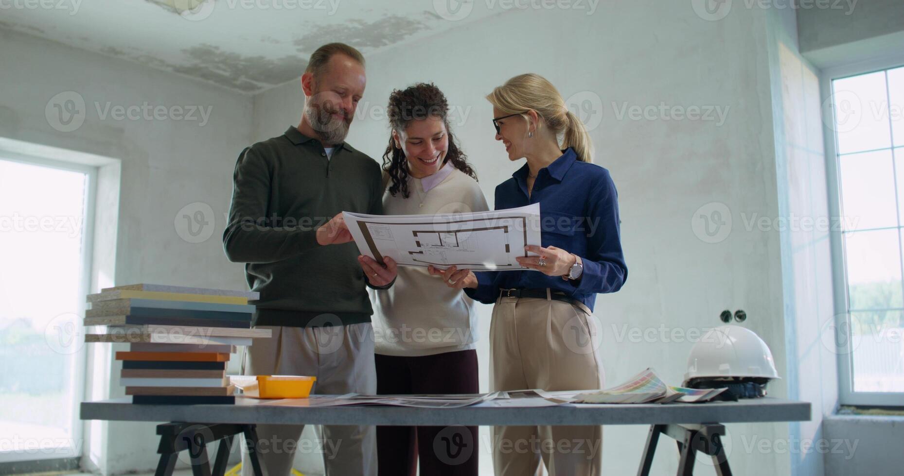 Happy customers study the design project of the house with the designer. Work on a construction site photo