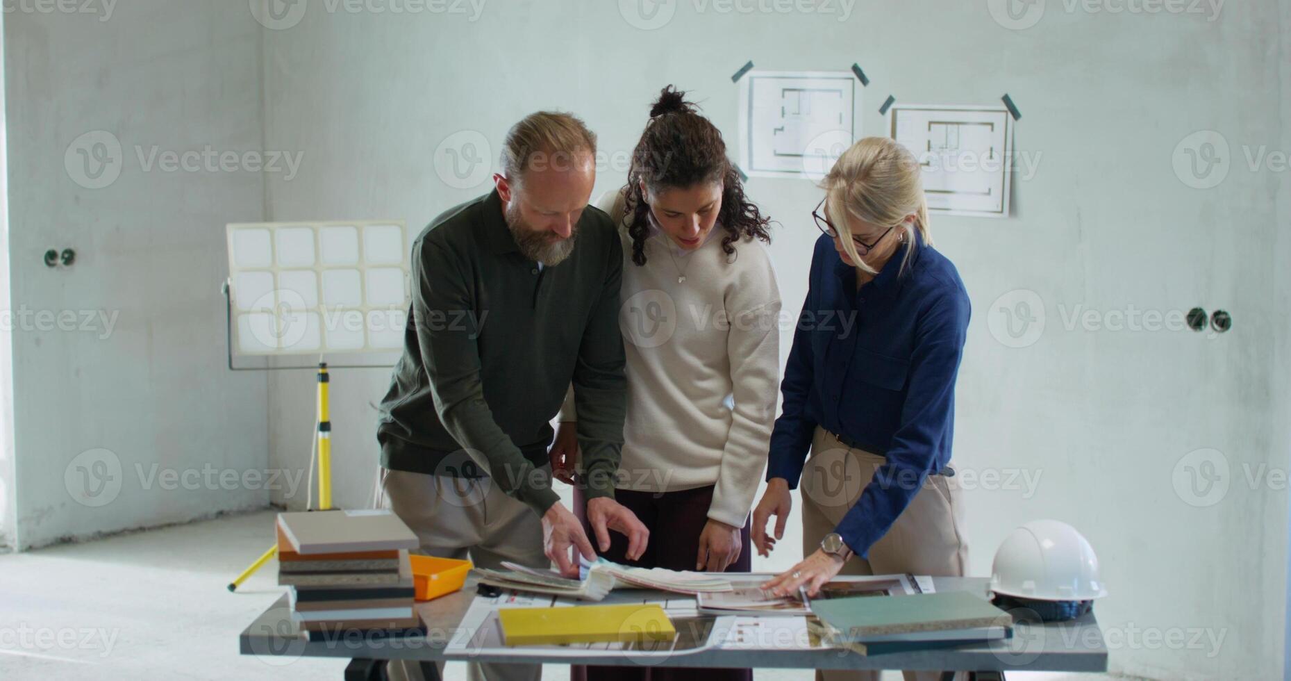 Customers choose the color of the house painting while standing on a construction site. They consult with the designer photo