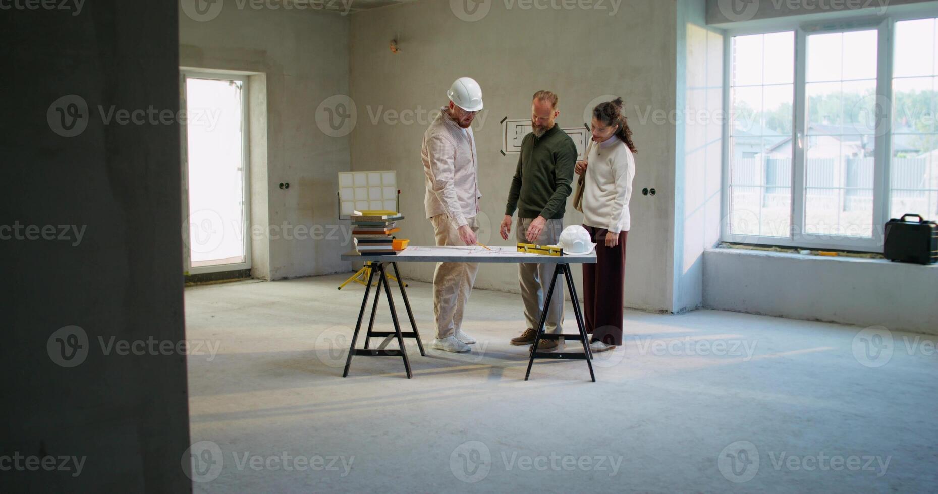 The foreman is talking to a married couple, discussing a house construction project photo