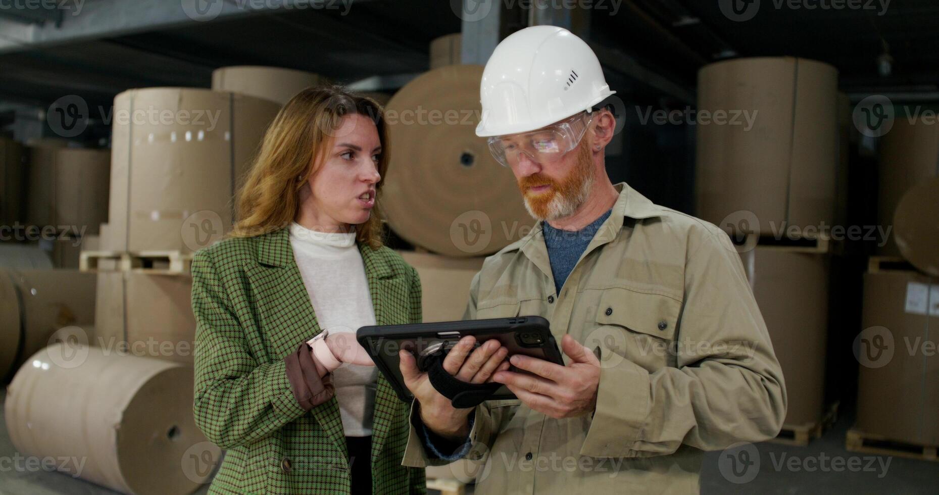 A paper mill worker is talking to the boss with a serious look. A man holds a tablet in his hand photo