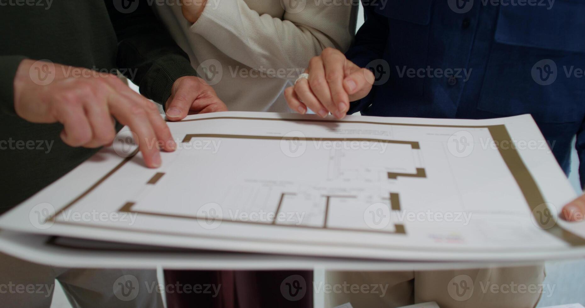 The designer shows the project of the house to the clients. The moves from close-up of their hands to a general plan photo