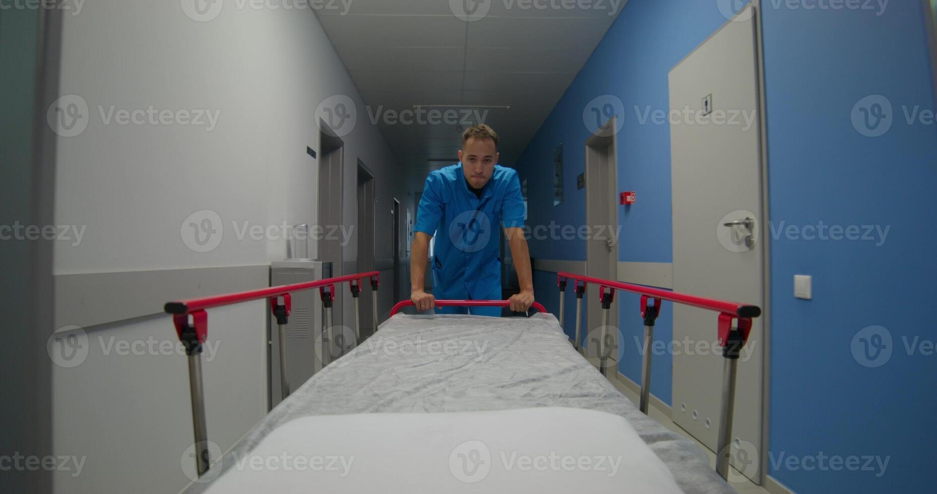 An orderly carries an empty gurney along the hospital corridor. Work at the clinic photo