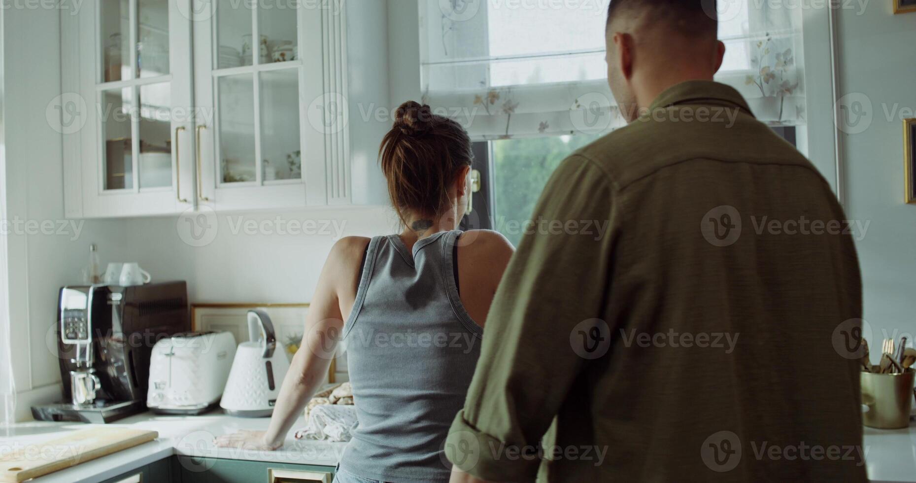 A family quarrel. A man and a woman are fighting in the kitchen at home. The woman turns away when the man shouts at her photo