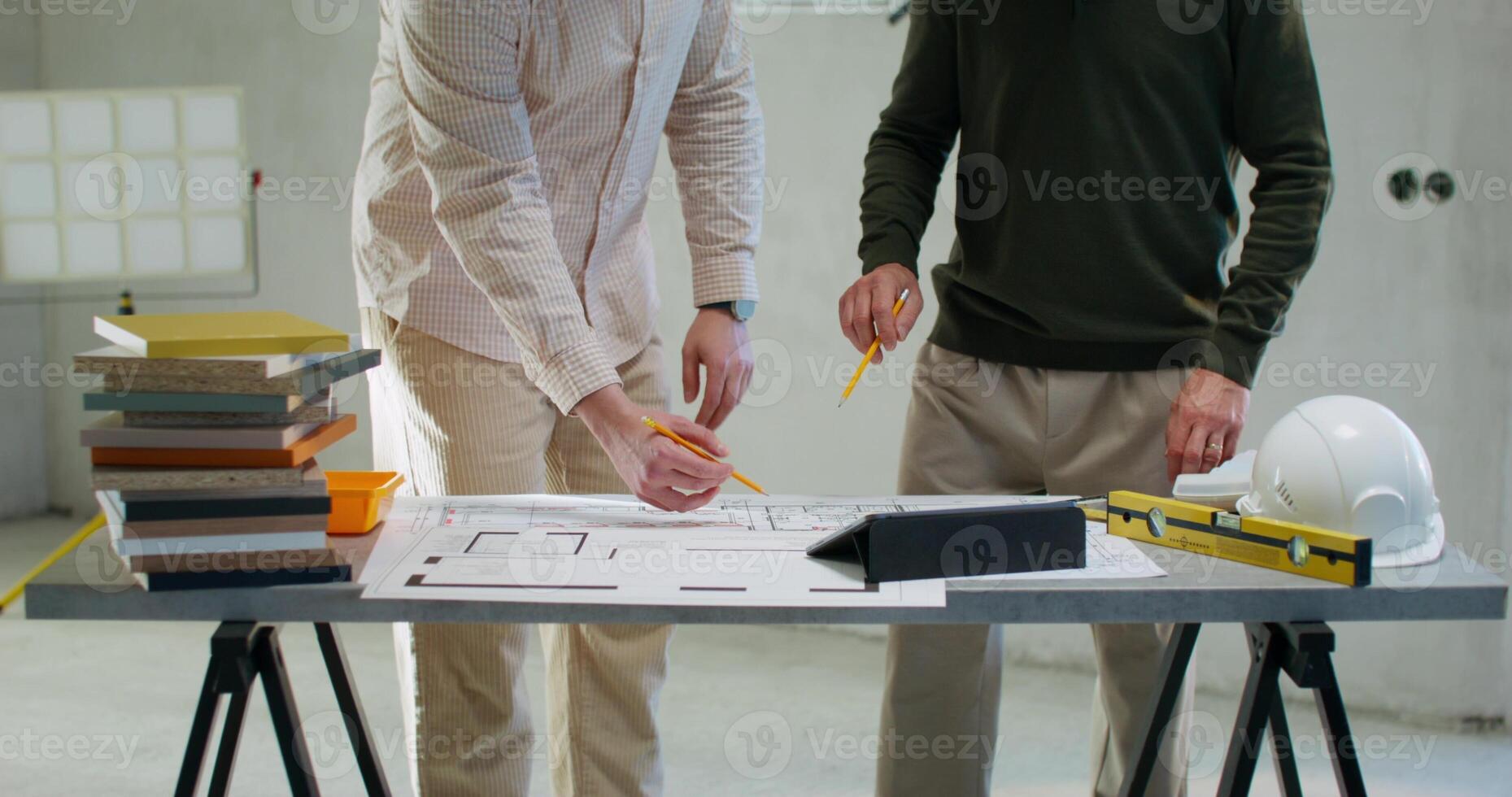 The foreman communicates with the customer, they study the house plan standing in a room without decoration photo