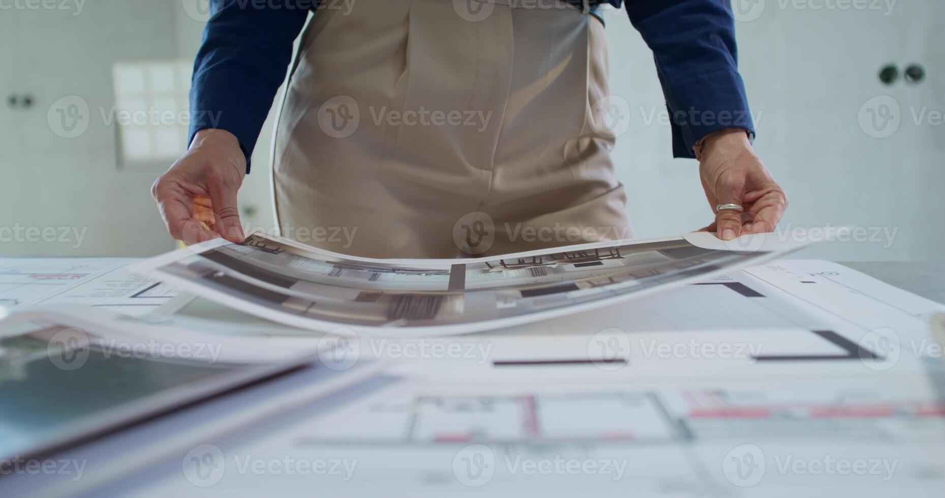 A businesswoman studies the design project of a house while standing in a room without decoration. Close-up of her hands, an unrecognizable person photo