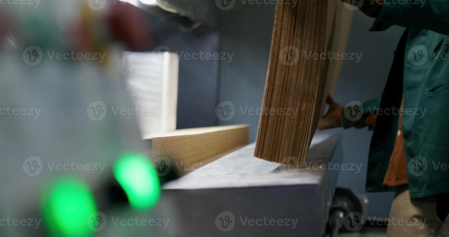 Working in a paper mill. A man drops stacks of cardboard into a machine photo