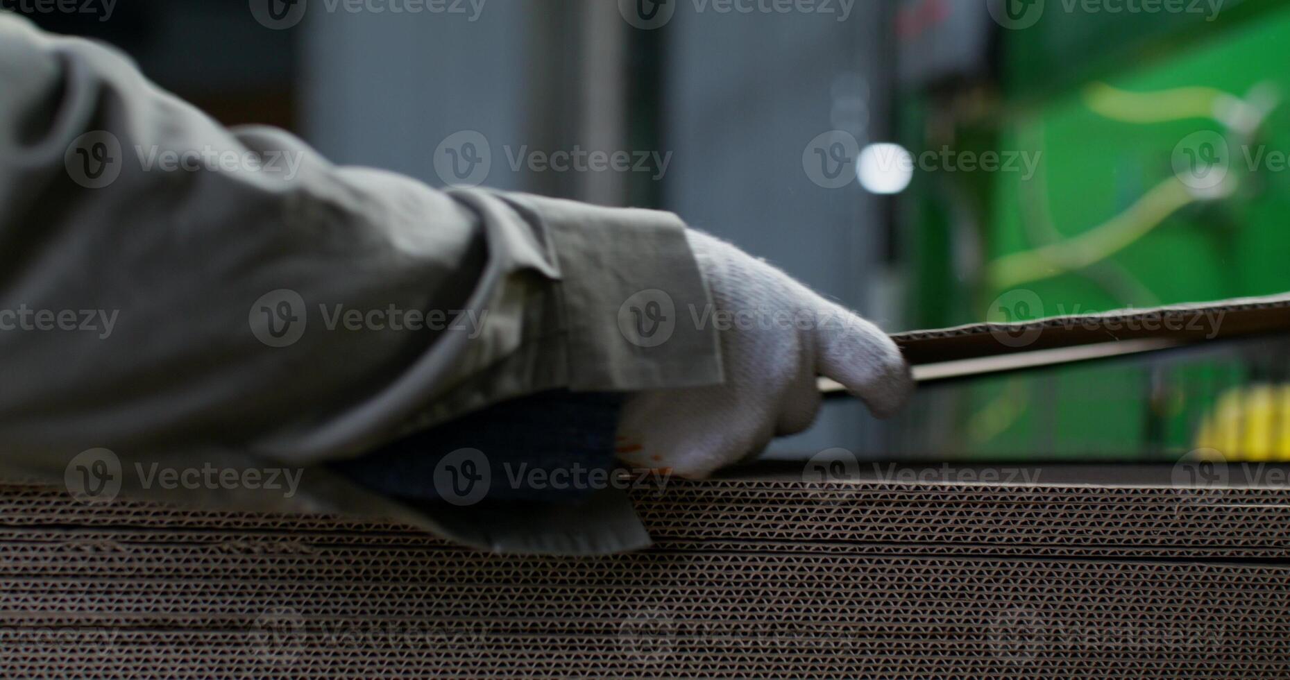 Cardboard production. Close-up of the hands of factory workers in protective gloves. The cardboard sheets are stacked photo