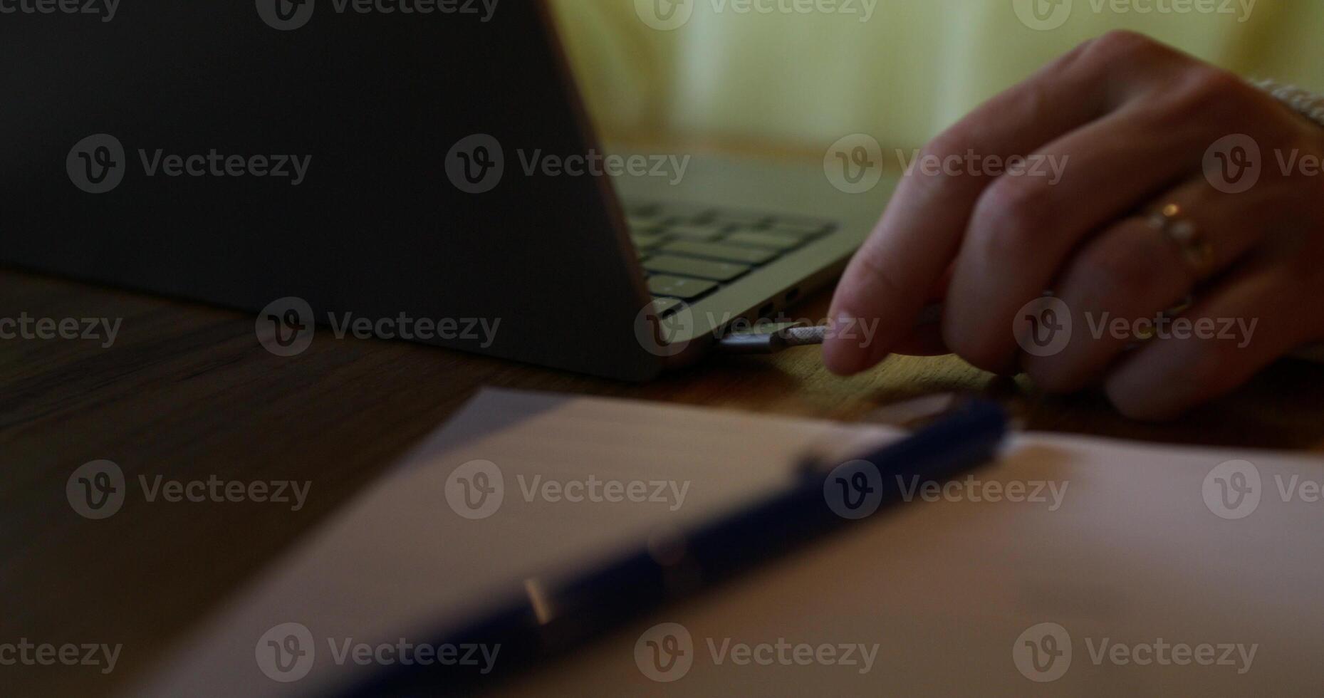 A woman inserts a charging cable into a laptop, close-up of her hands, an unrecognizable person photo