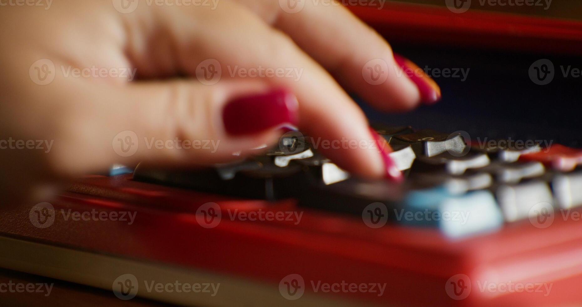 A woman's hand enters numbers on an outdated calculator. Close-up, unrecognizable person photo