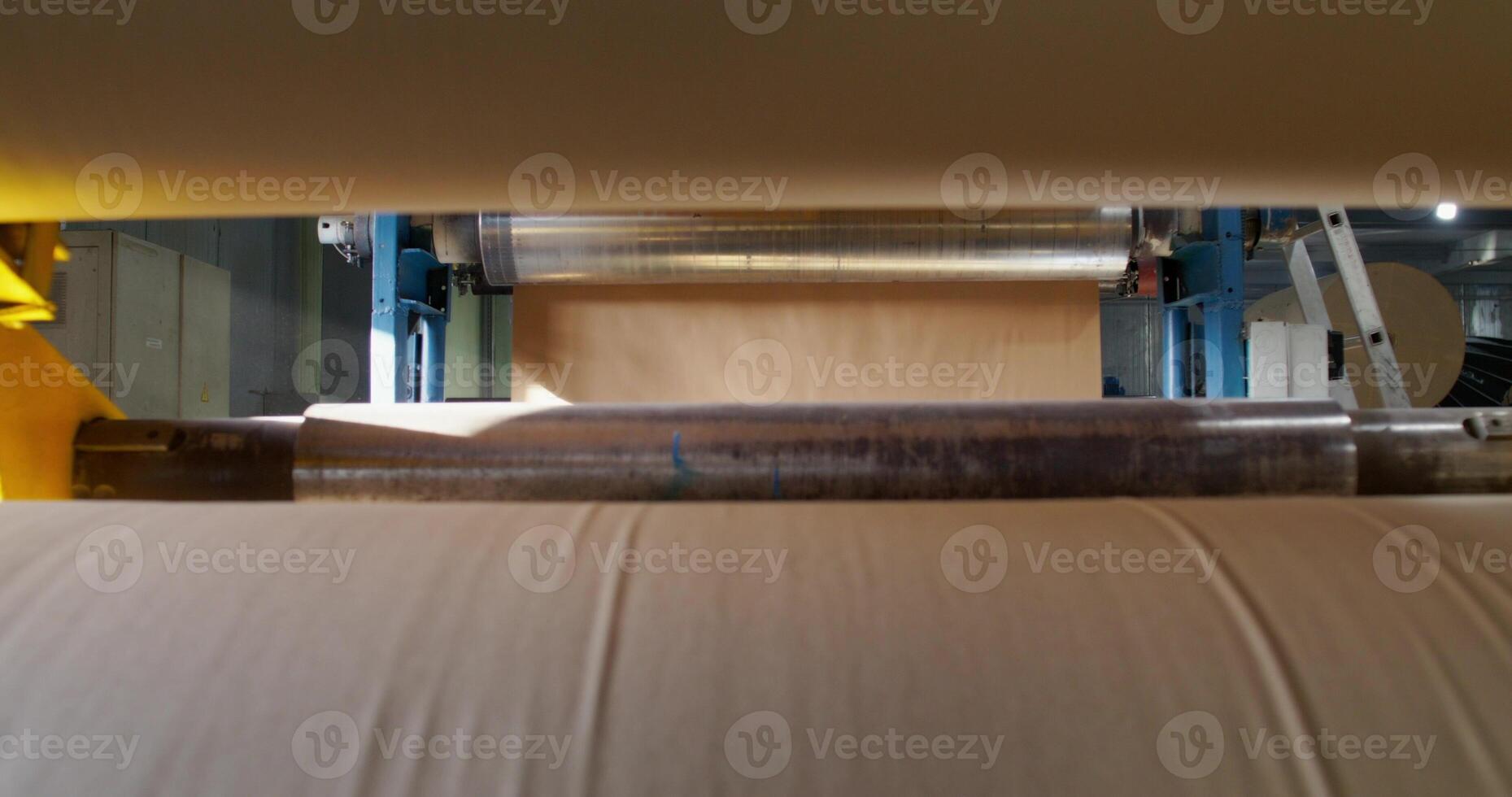 A paper factory. The sheet of paper is processed in the machine. Close-up of the production photo