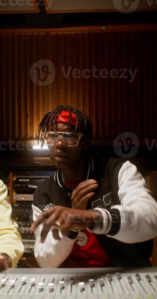 The singer listens to his song while sitting near an audio mixer in a recording studio. He's talking to the sound engineer. photo