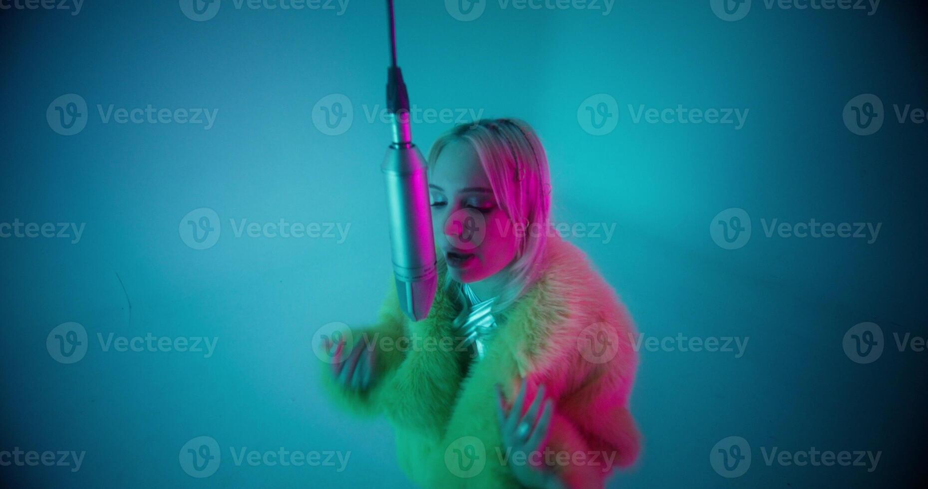 The singer moves her hands rhythmically when she sings into the microphone. Studio photo