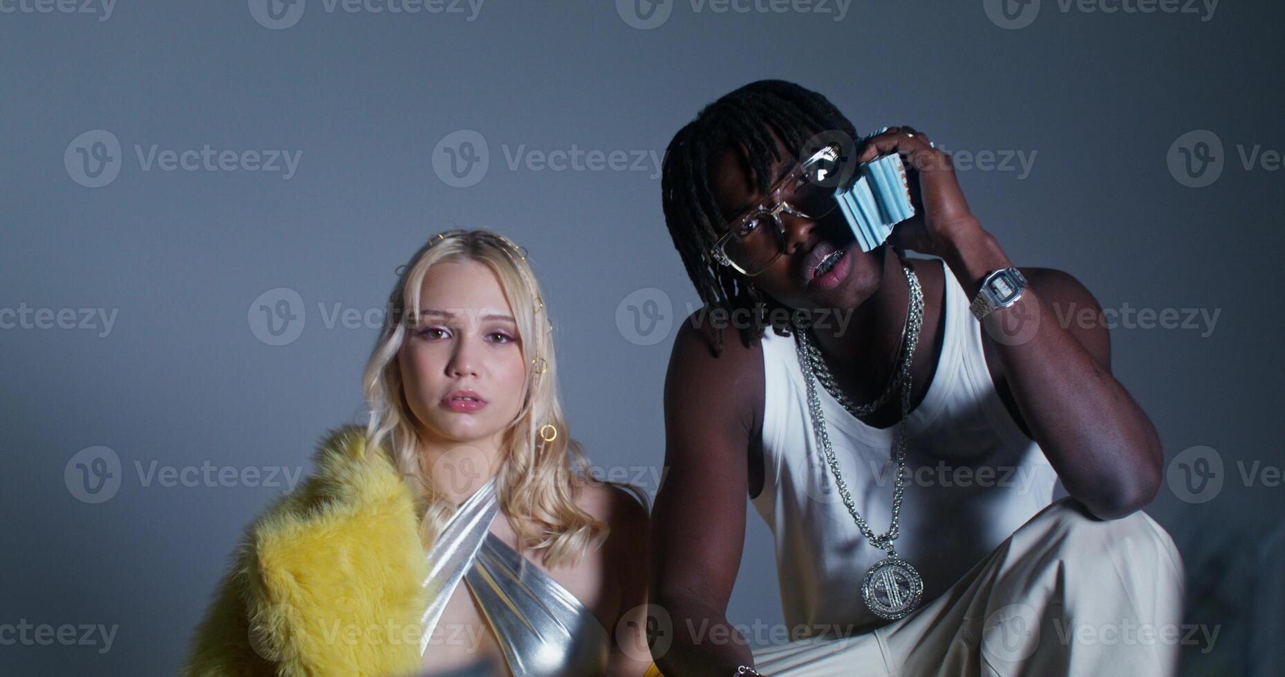 Photo shoot with money in the studio. A man and a woman of different nationalities look at the camera with serious look