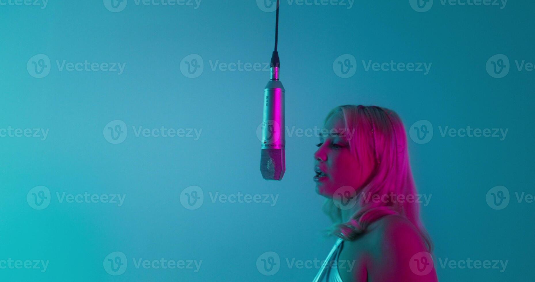 A rapper and a glamorous woman sing into a microphone together. Recording music in the studio photo
