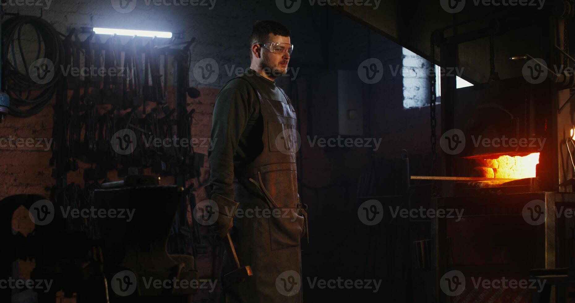 A man in an apron is standing in front of a blacksmith photo
