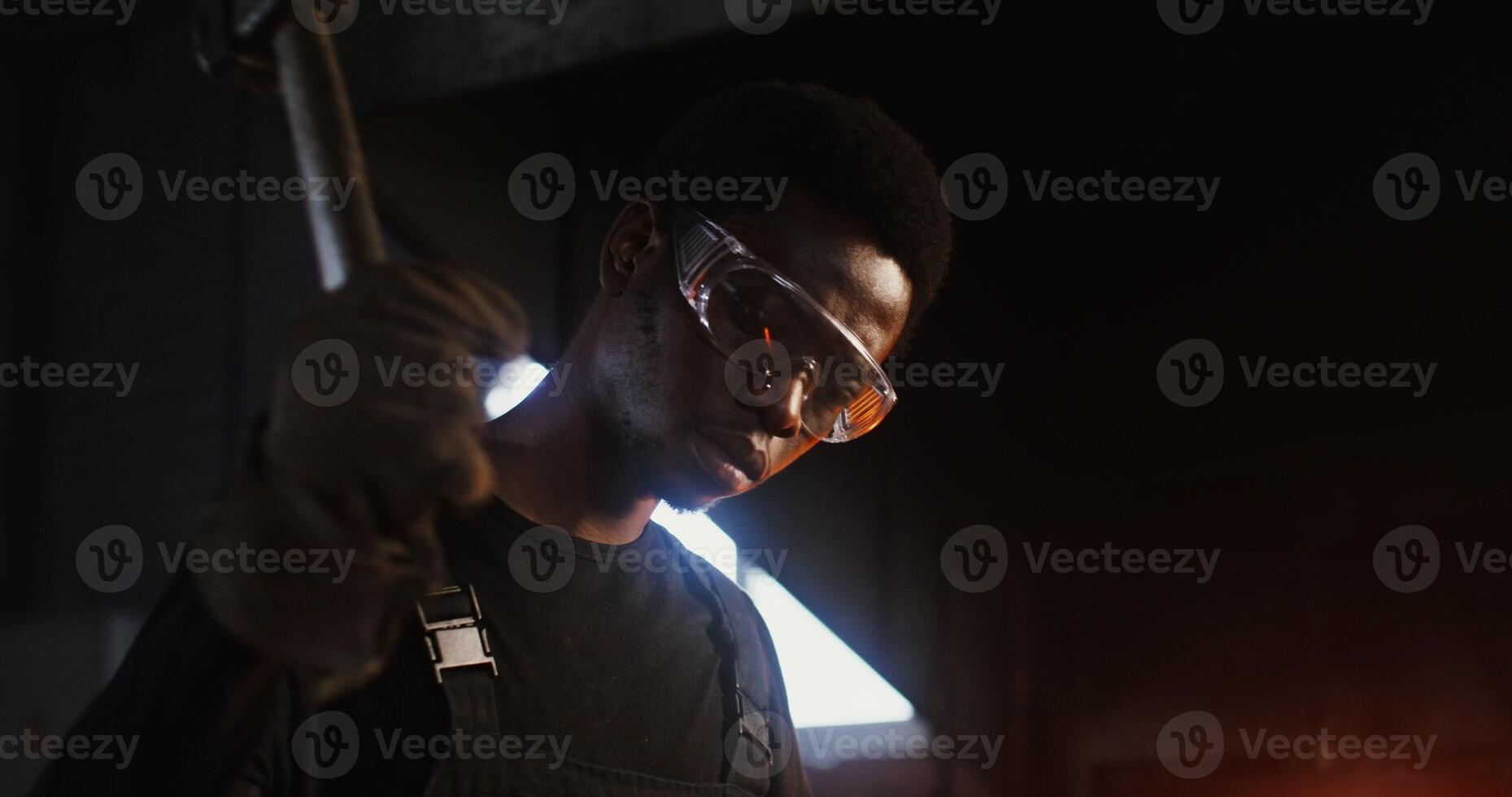A man in a black overalls holding a hammer photo