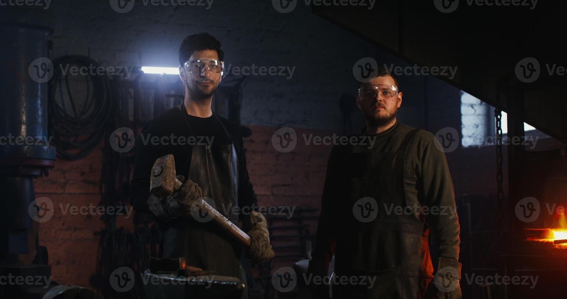 Two men in blacksmithing gear standing in front of a furnace photo