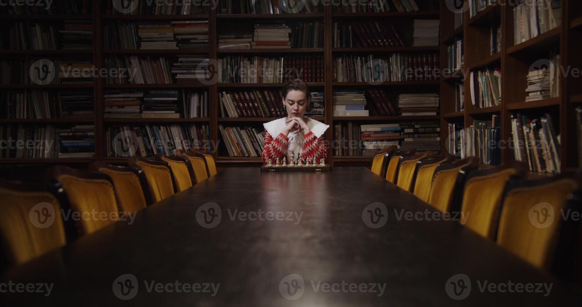 A man sitting at a table in front of bookshelves photo
