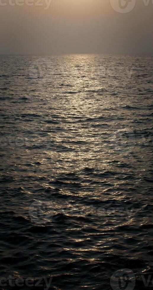 A bright streak of sunlight is reflected in sea water with small ripples of waves, vertical . 4k , red komodo photo