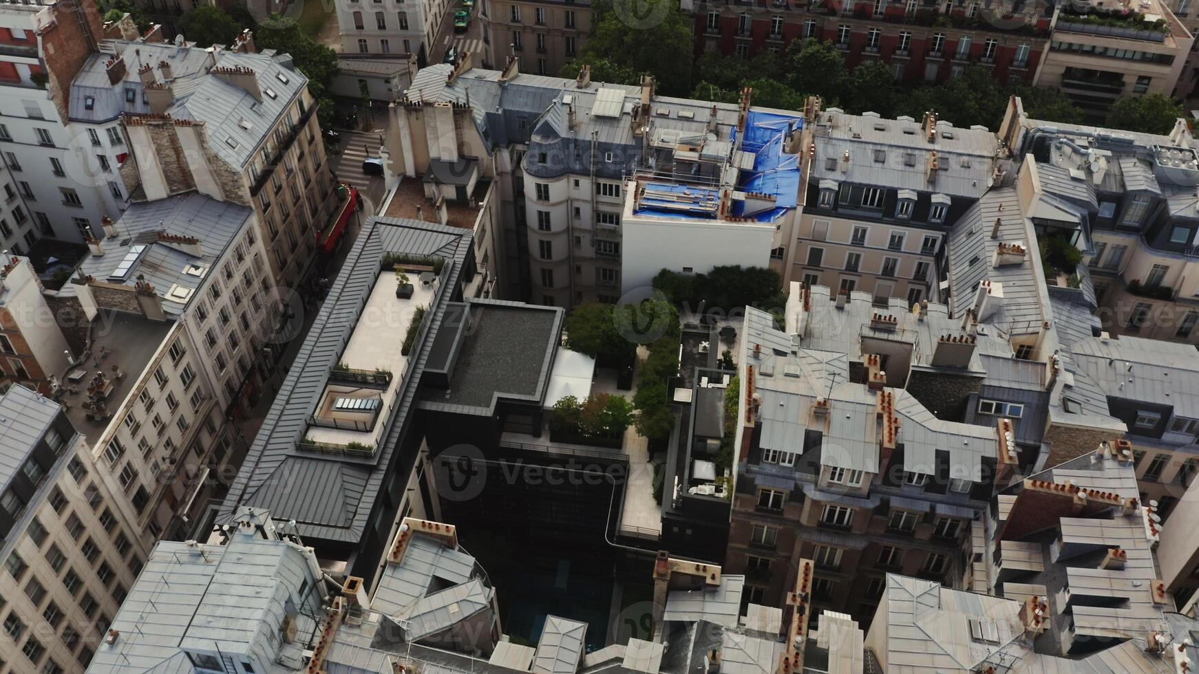 The view from above on the roofs of the traditional houses of Paris gradually turns to the general panorama of the city with the Eiffel Tower towering over other buildings. France, Paris, drone photo