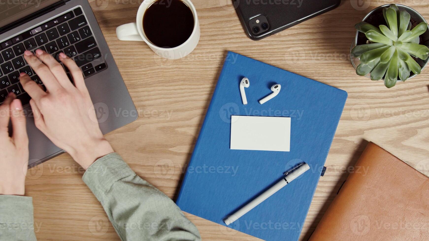 A business card sized white paper lies on a notepad on the desktop of a modern young woman typing on a laptop. Close-up of female hands, no face. Place to copy. in 4k, red komodo photo