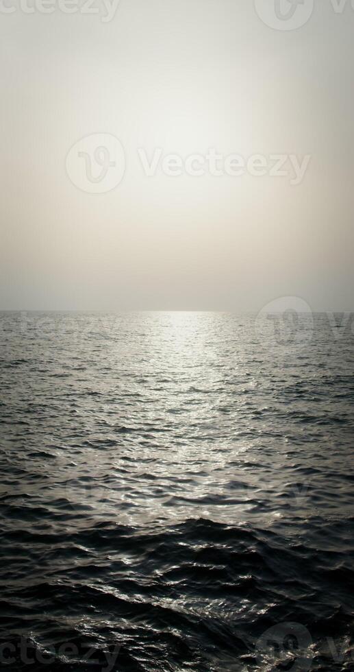 The light of the setting sun is reflected in the sea ripples. Small waves, you can not see the shore. Sea or ocean water. Vertical . 4k , red komodo photo
