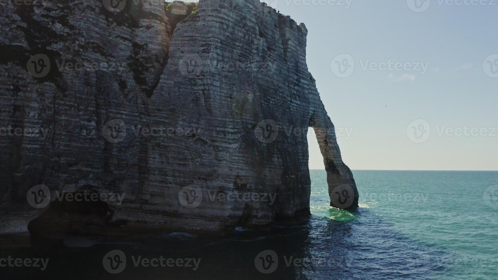 The drone flies through one of the natural arches, revealing a view of the mysterious beach at the foot of sheer cliffs. Etretat, France photo
