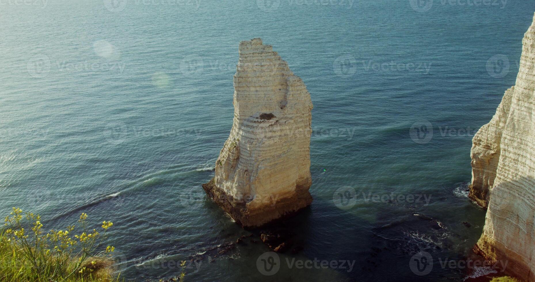 A detached limestone peak sticks out of the sea water, not far from the coast. Top view from the top of the hill. Etretat, France. 4k , red komodo photo