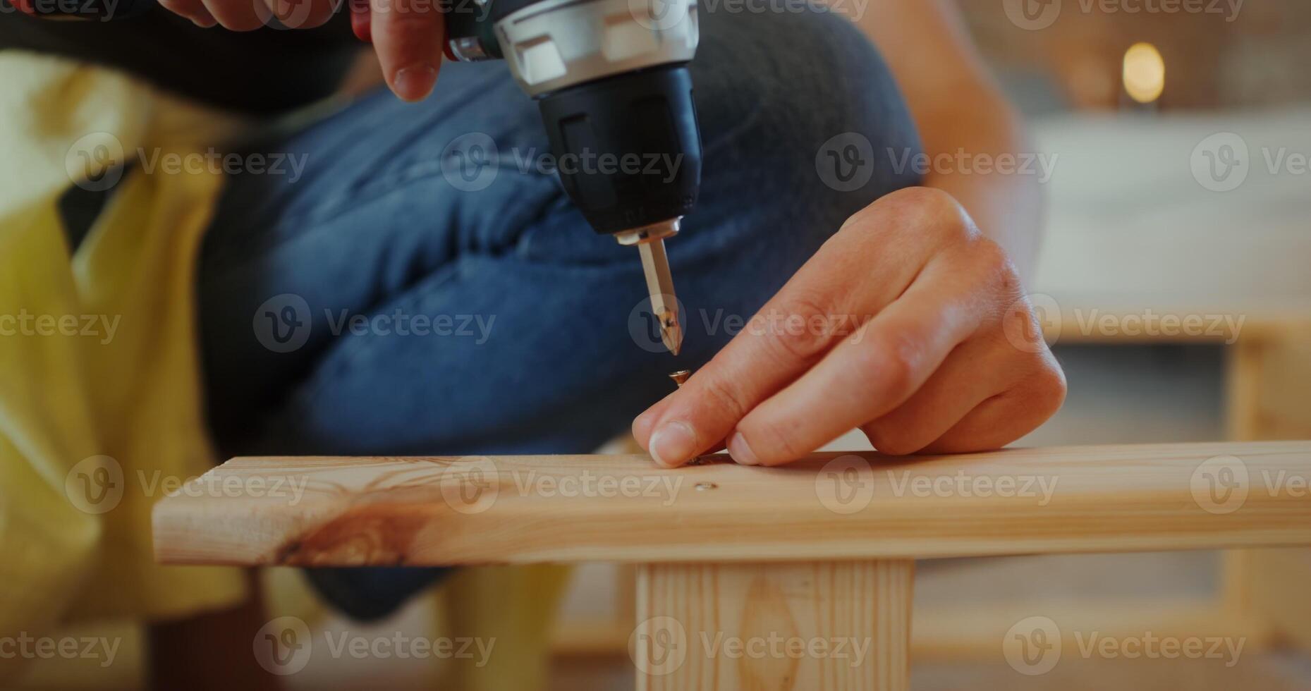 A woman assembles a wooden shelf using a screwdriver in a stylish home interior. Hands close-up, no face photo