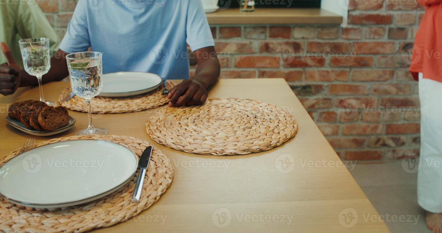 A woman puts a baking tray with a roast on the table, a close-up of her hands photo