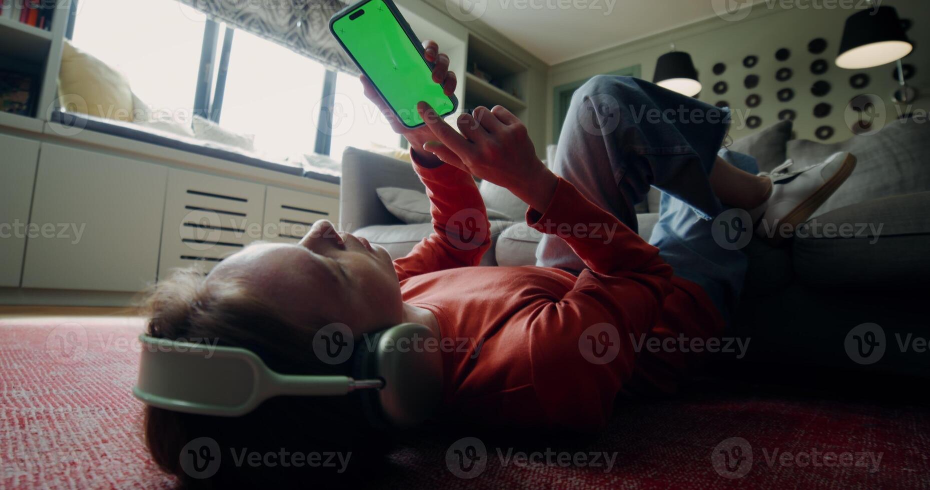 A woman laying on the floor with headphones on and a tablet computer photo