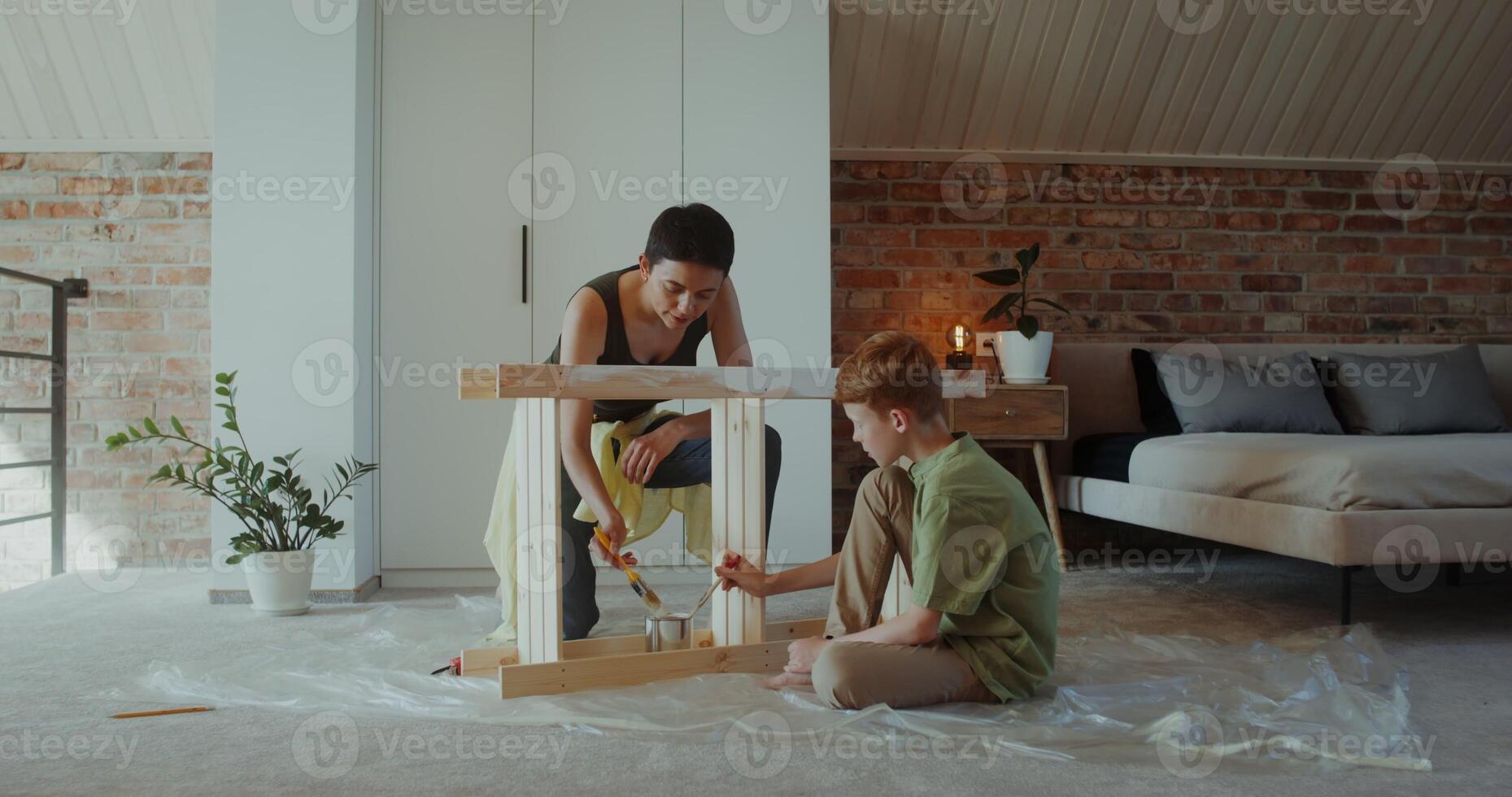 Mom and son paint a wooden rack with a brush in a stylish home interior, working together, teaching a child photo