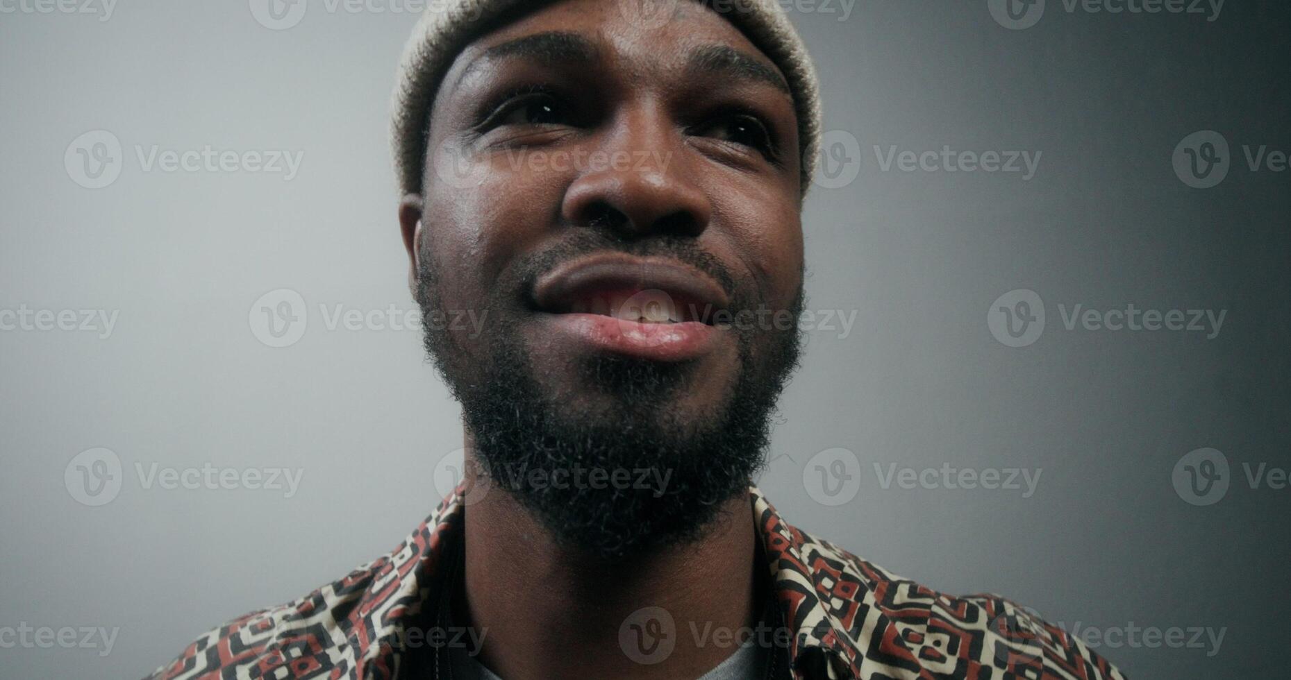 A stylish bearded man swears and screams, waving his arms and looking at the camera, standing on a gray background in the studio photo