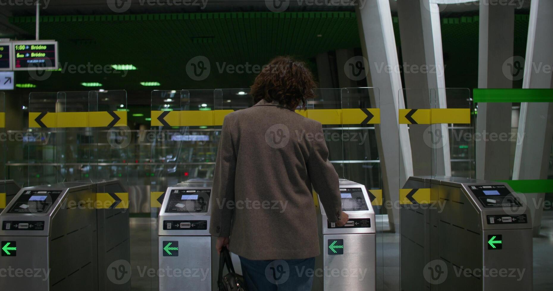 A woman in casual clothes passes through the turnstiles of the subway, rear view, unrecognizable person photo