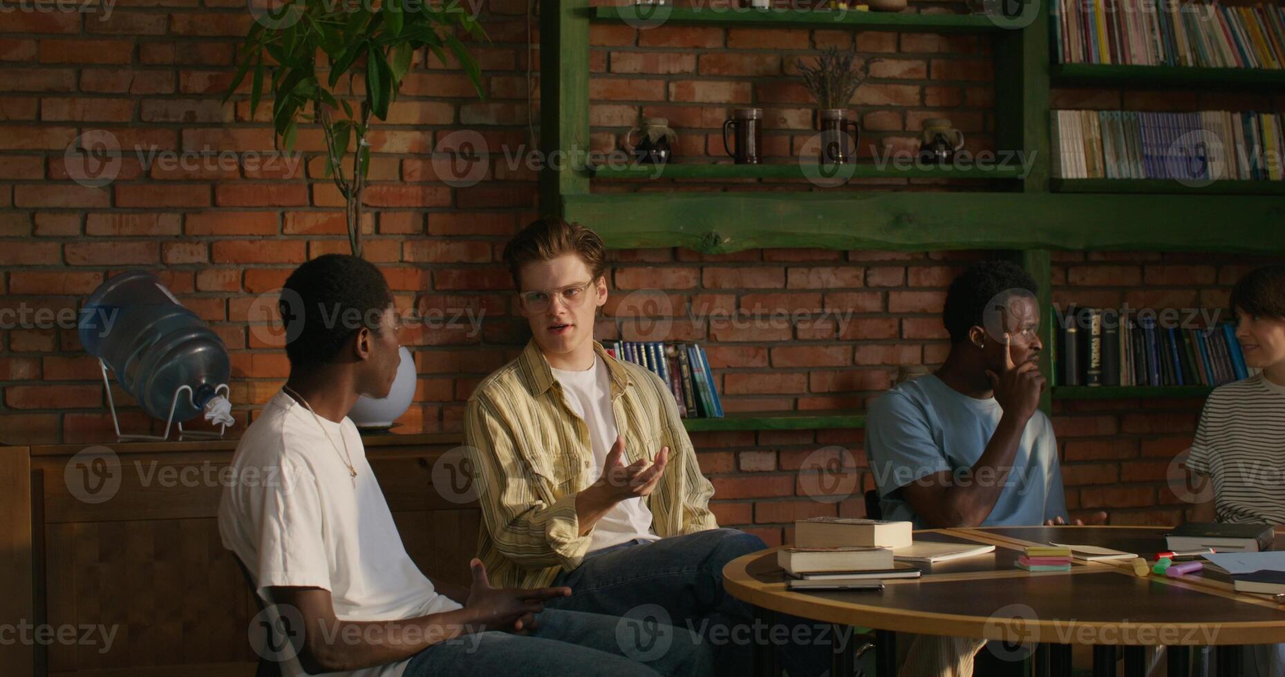 Bible Study Group. Young people talk in pairs. They are sitting at a round table in the room. photo