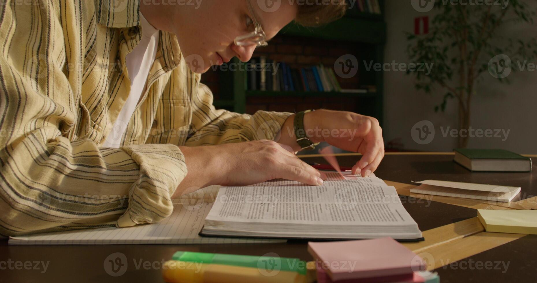 A man is studying the Bible while sitting at a table indoors. He reads different translations. Daylight photo