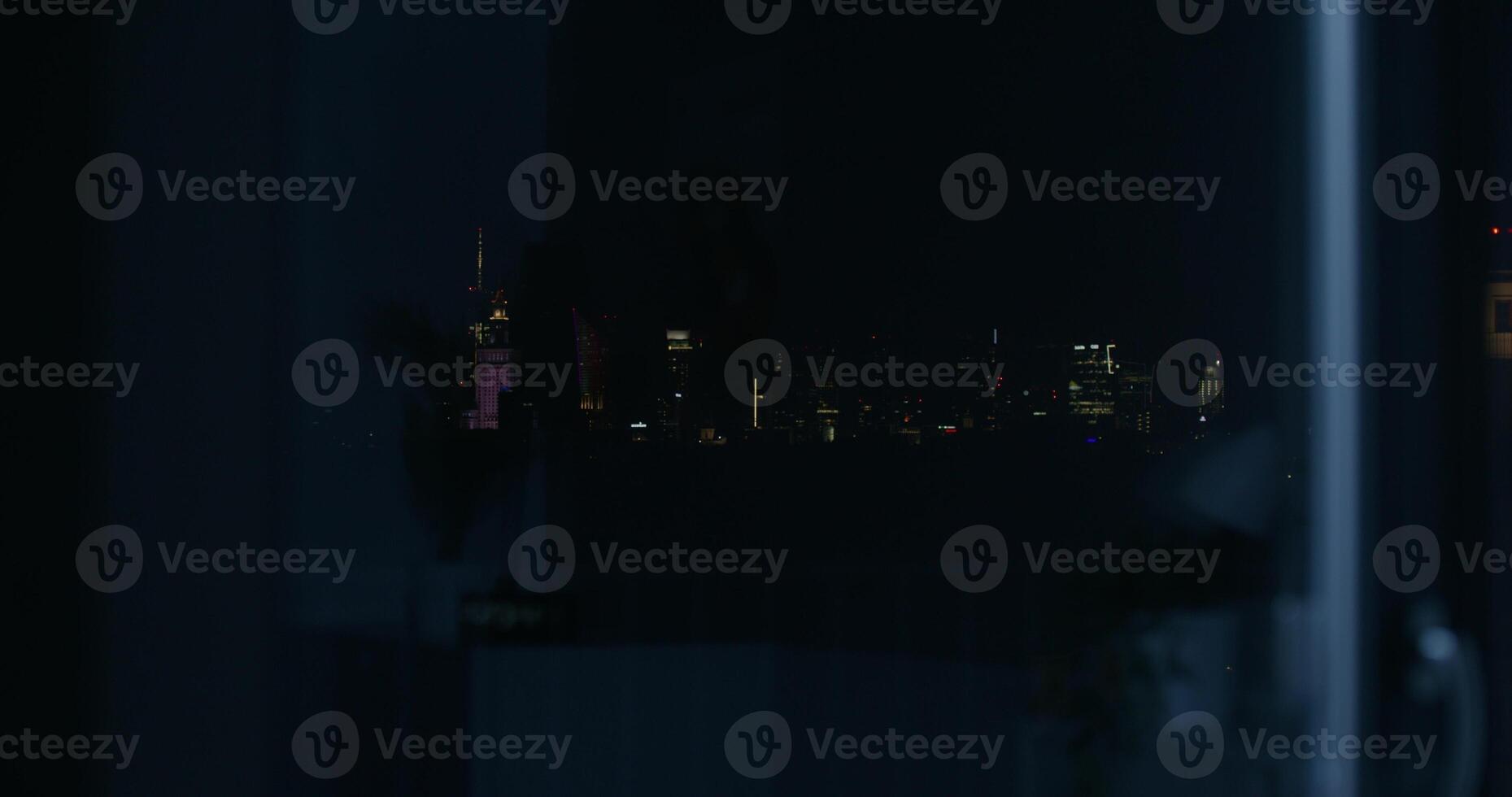 View from the open window of the night city. The lights of the skyscrapers of the city center in the dark photo