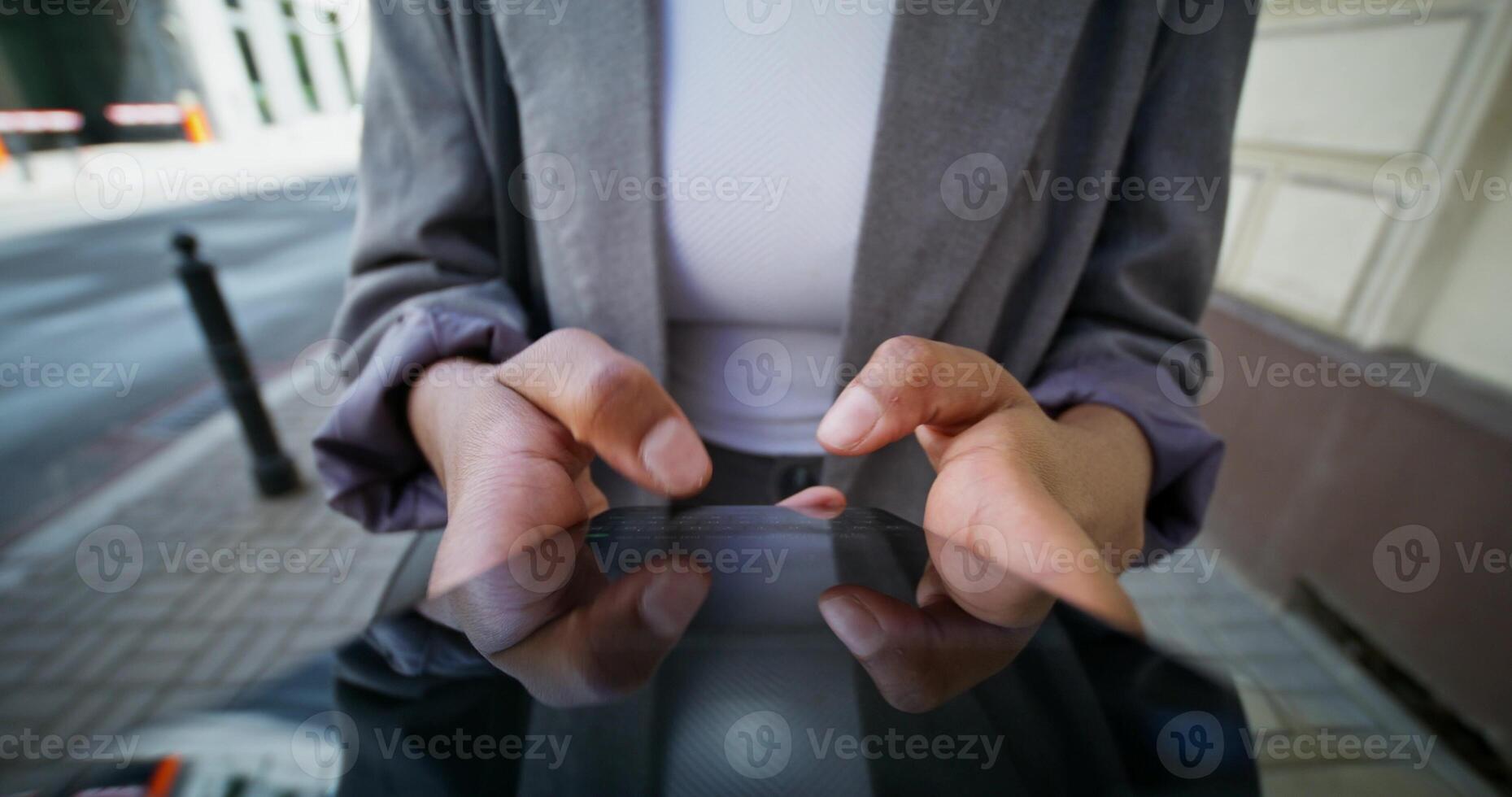 A woman in formal clothes uses a mobile phone walking along a city street. Close-up of a mobile phone screen, an unrecognizable person photo