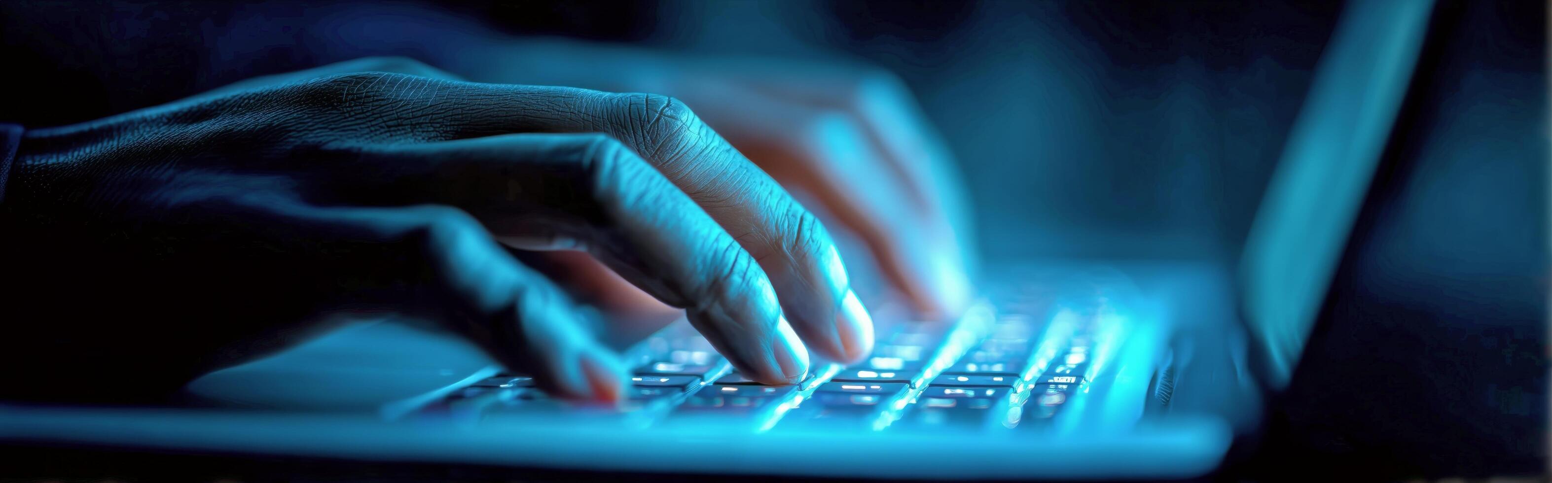 Hands Typing on a Laptop Keyboard Illuminated by Blue Light in a Dark Environment photo