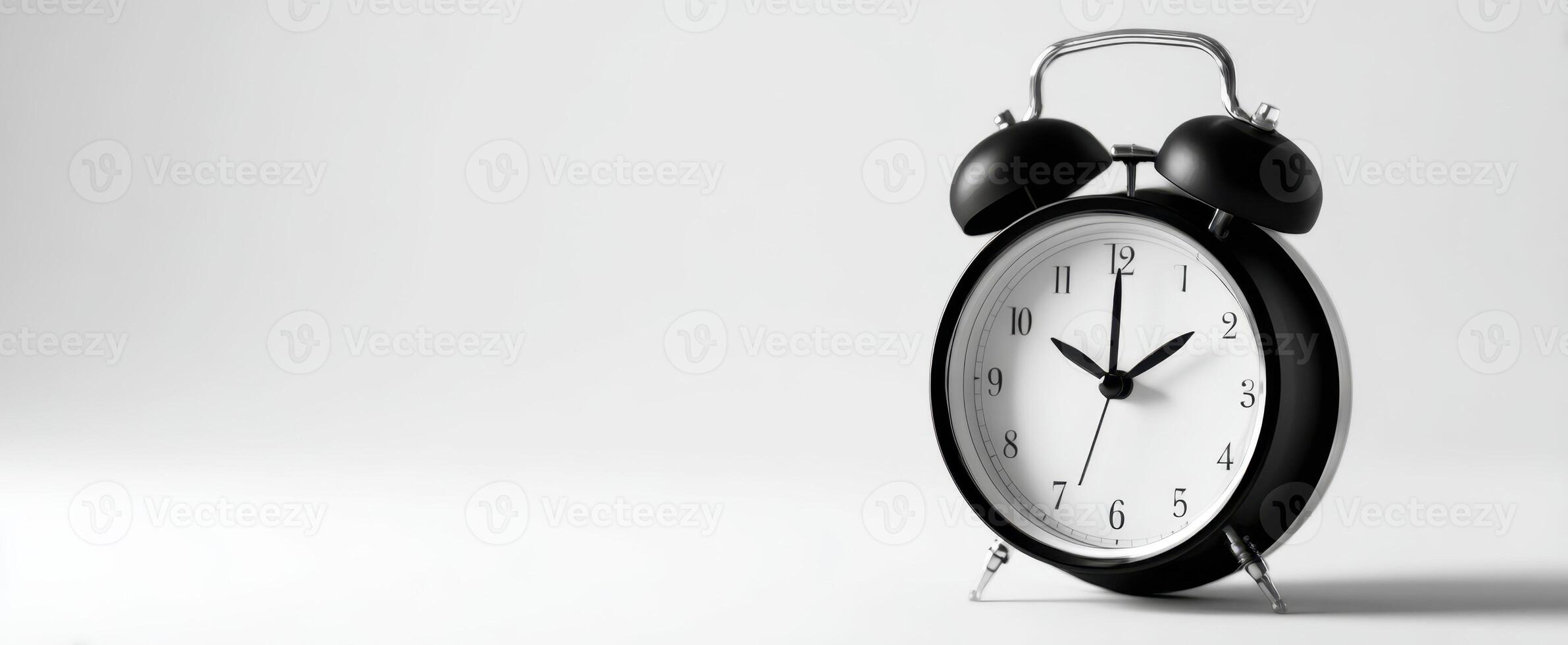 The classic black alarm clock showcasing time in a minimalist setting. photo