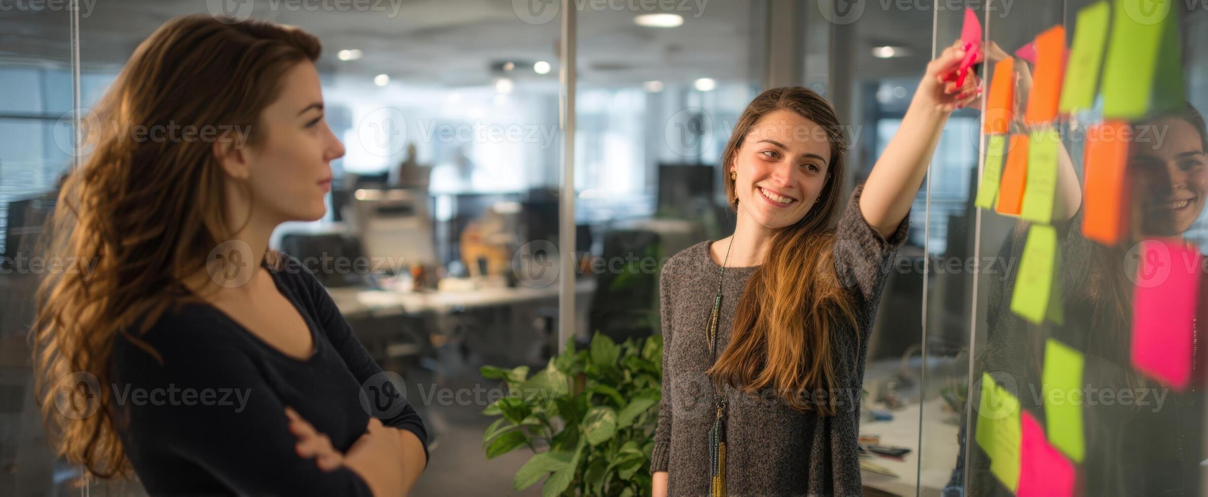 The women collaborating over colorful sticky notes in a modern office setting. photo
