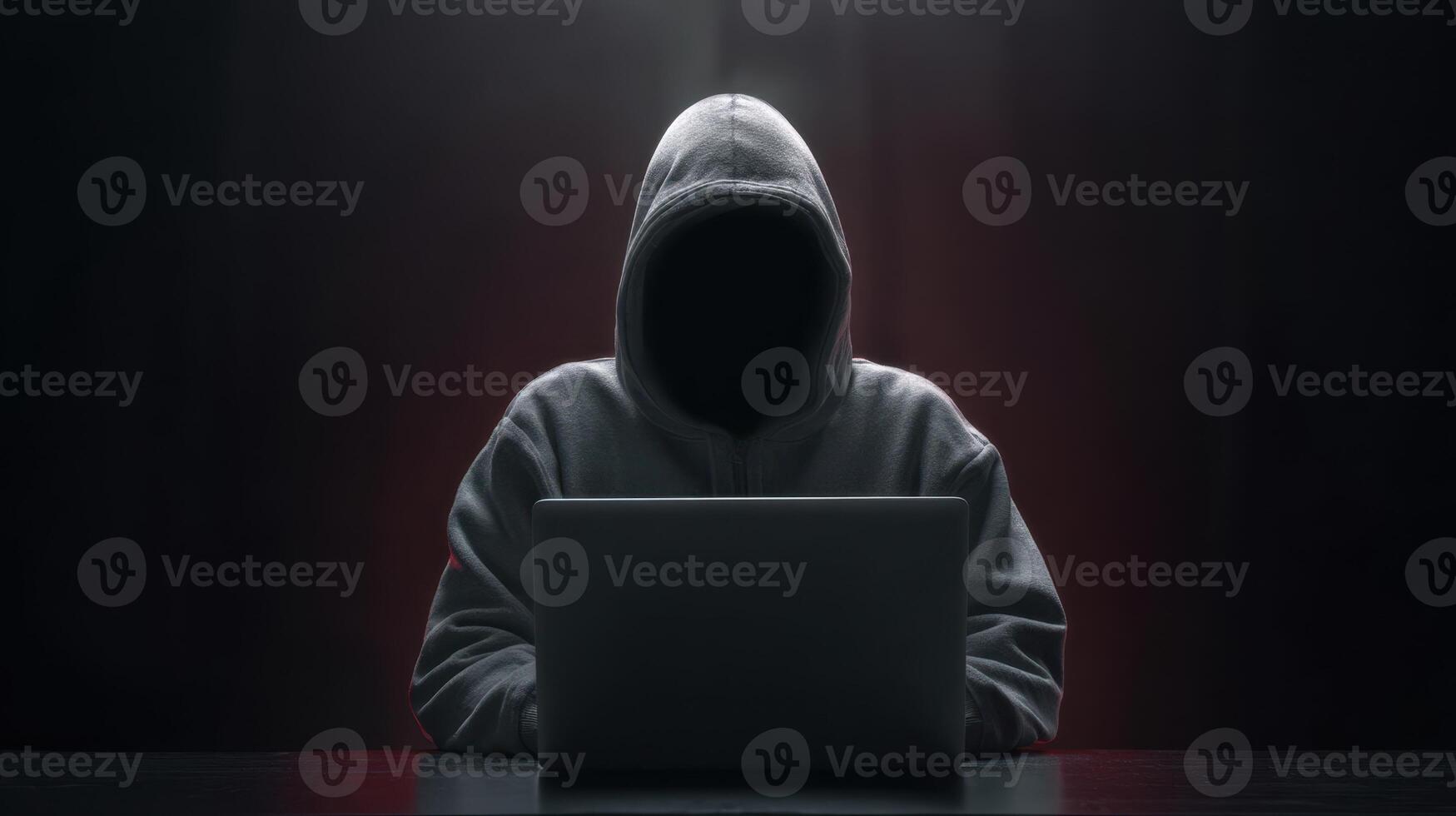 The hooded figure using a laptop in a mysterious dark environment. photo
