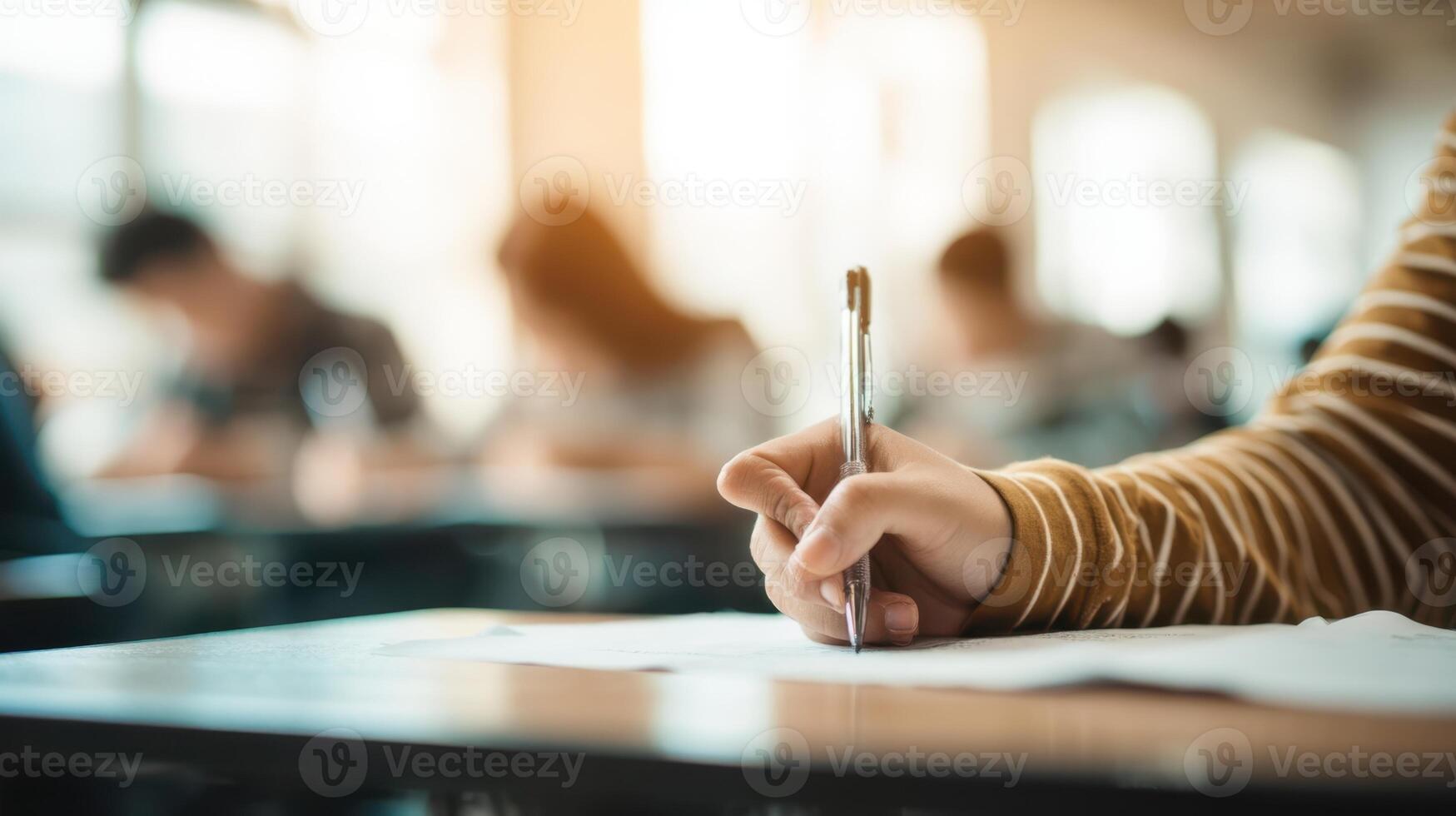 The student writing notes during an exam in a busy classroom setting. photo
