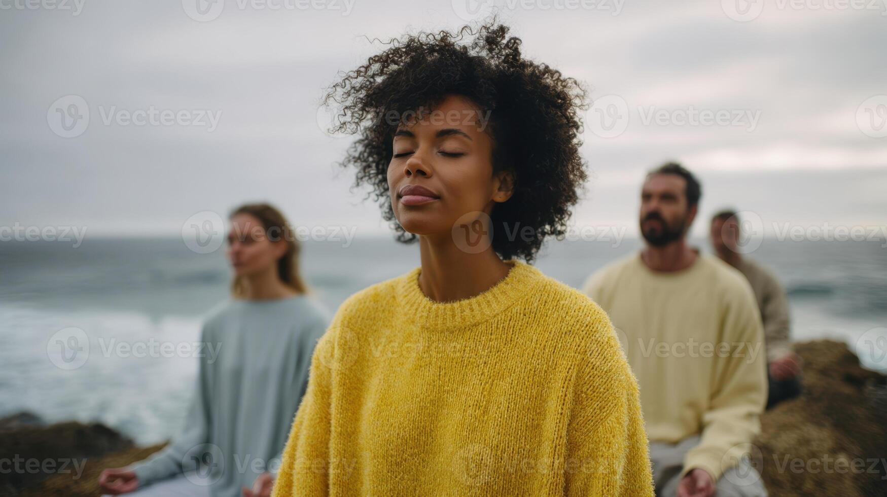 The serene group of individuals meditating by the beautiful ocean shore. photo