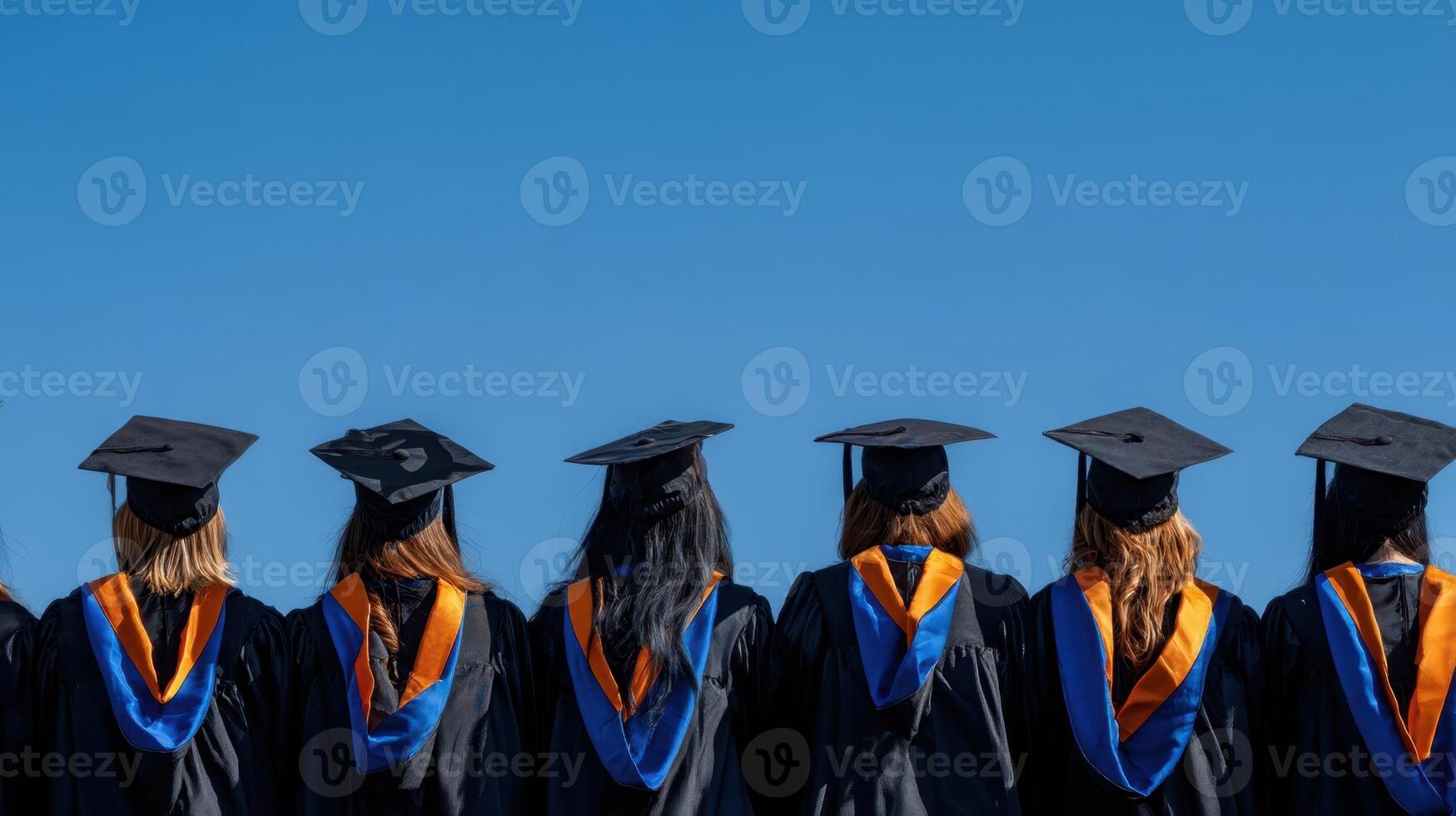 The group of graduates celebrating their achievements under a clear blue sky. photo